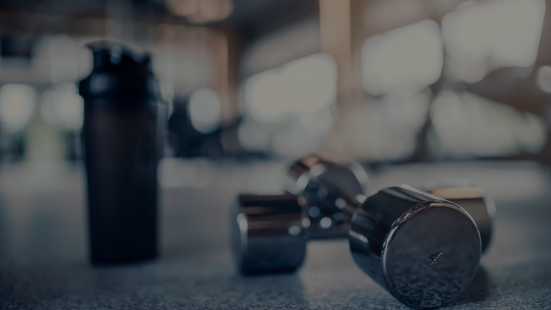 haltères posées au sol avec une gourde noir en arrière plan