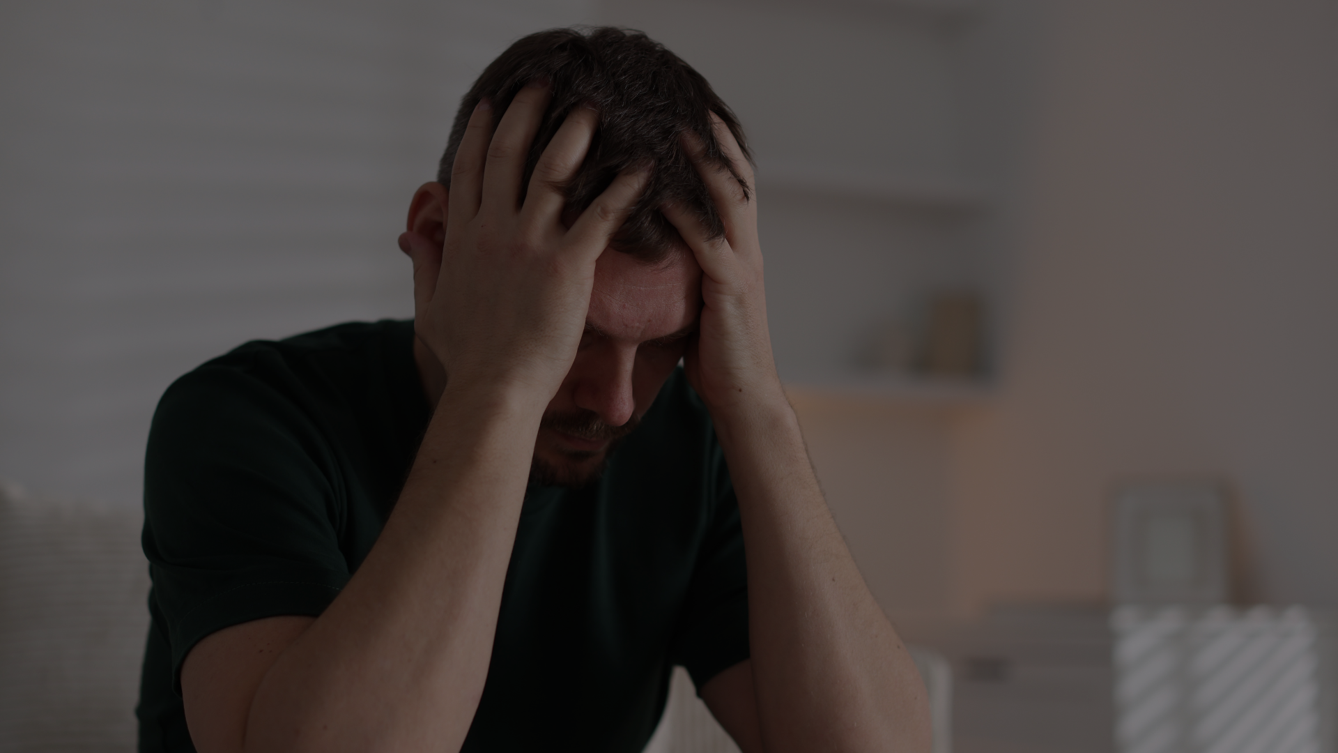 homme qui tient sa tête dans ses mains